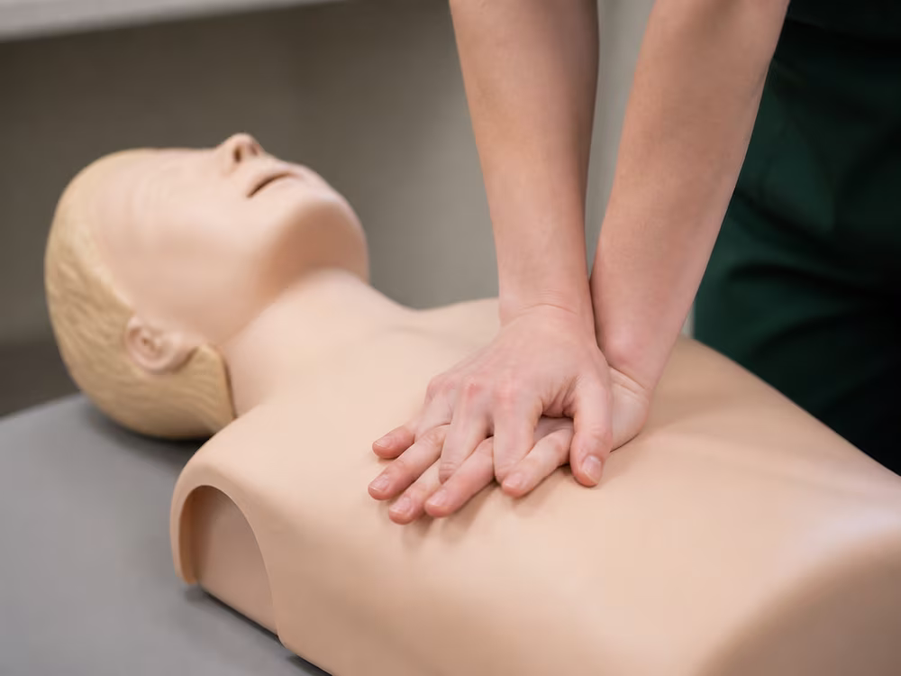 Close-up of hands performing chest compressions on a CPR training manikin