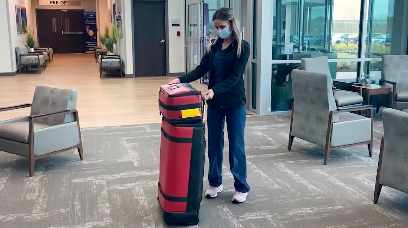 Medical professional with a red rolling CPR Go-Kit case in a clinic waiting area