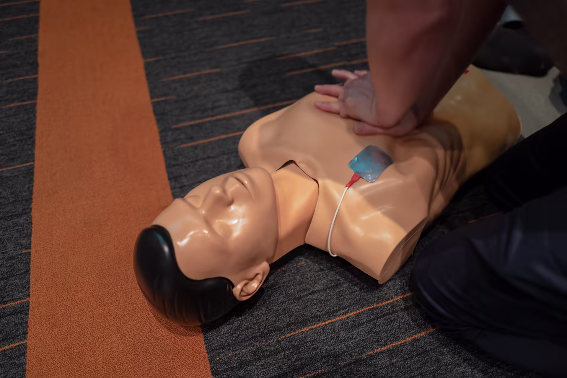 Employee practicing chest compressions on a feedback manikin