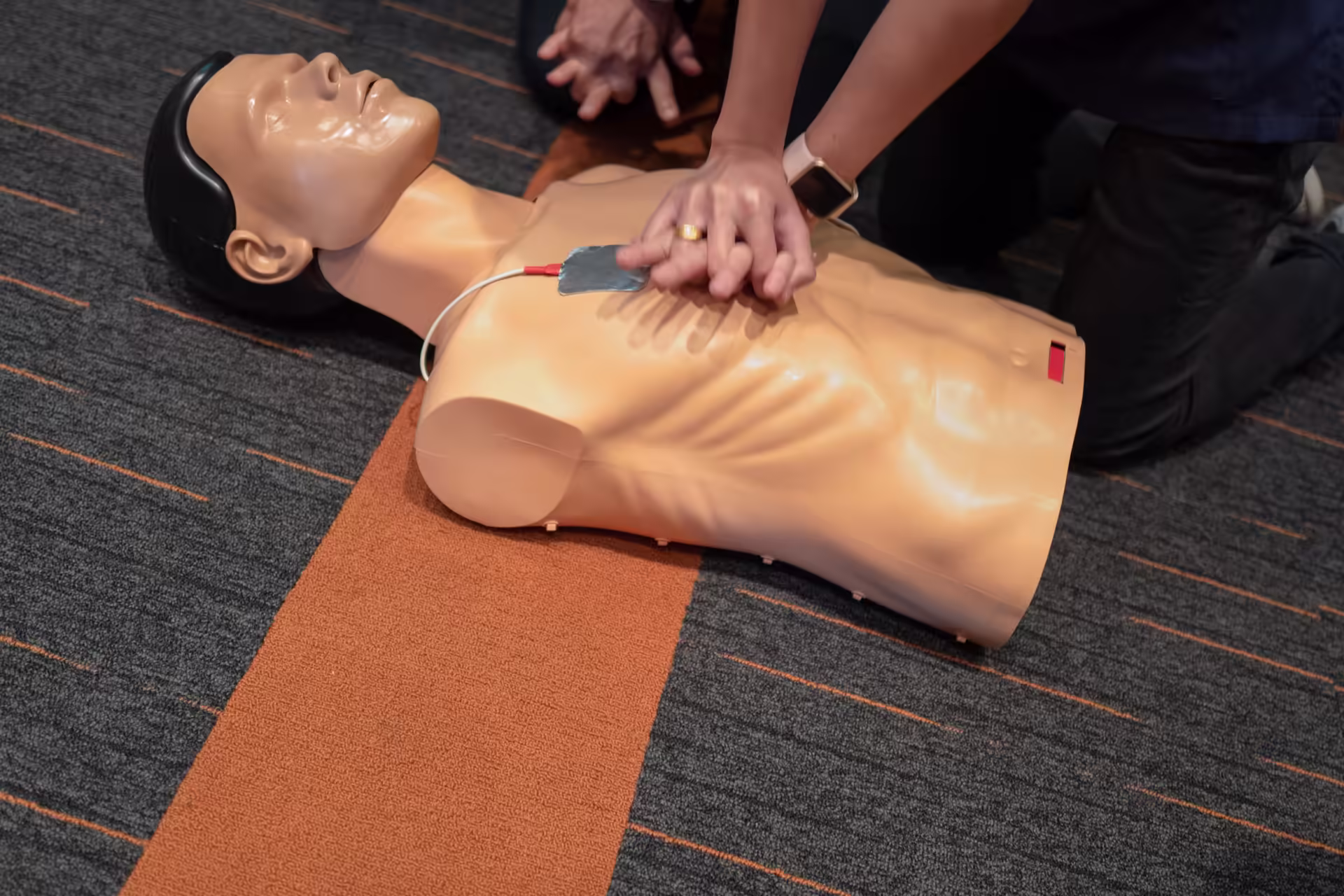 Hands performing CPR compressions on a training manikin